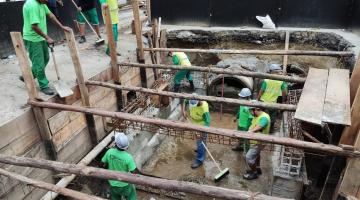 trabalhadores em buraco onde é realizada obra #paratodosverem