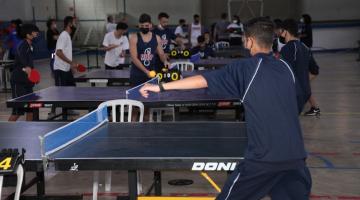 estudantes jogando tenis de mesa em ginásio #paratodosverem