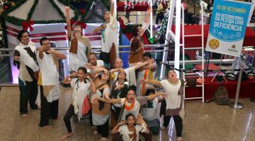 Jovens estão cantando e fazendo performance. Eles estão em meio a uma decoração de Natal. #Pracegover