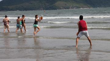 casal joga frescobol na praia #pracegover