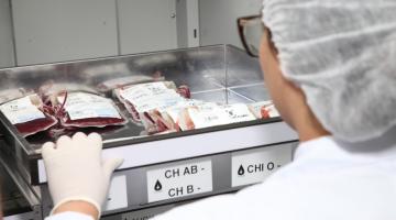 mulher está de costas segurando gaveta aberta com bolsas de sangue. #paratodosverem 