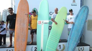 os homens vencedores da categoria open com seus pranchões estão no pódio do número 1 ao 4. #paratodosverem