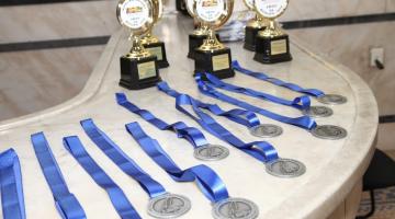 medalhas e troféus sobre uma mesa. #paratodosverem 