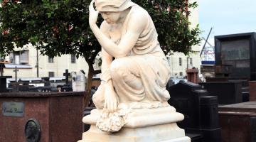 monumento em mármore de mulher ajoelhada e seguranda a cabeça que olha para baixo. #paratodosverem 