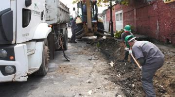 homens trabalhando em construção de sarjeta ao lado deum caminhão. #paratodosverem