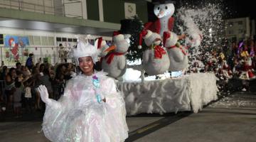 pessoa fantasiada desfila na frente de carro alegórico com boneco de neve #paratodosverem