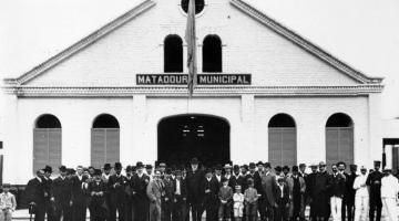 Fachada do Matadouro Municipal, com homens e crianças em frente. #pracegover