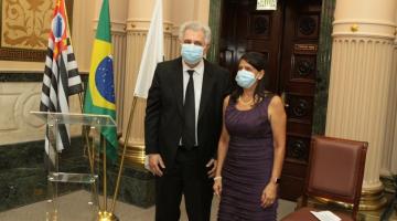 Alvaro Norberto e Ana Beatriz posampara foto em frente às bandeiras do Estado de São Paulo, do Brasil e de Santos. #paratodosverem