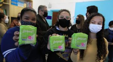 Meninas erguem pacote com absorvente #paratodosverem