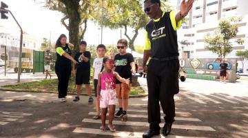 agente estende a mão e ensina crianças a atravessar a rua #paratodosverem