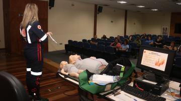 enfermeira com uniforme dá palestra em auditório. #paratodosverem