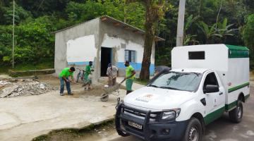 Homens trabalham em obra de prédio. Diante da calçada há um veículo da prefeitura estacionado. #paratodosverem