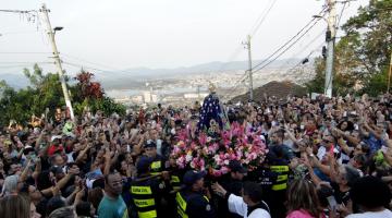 Imagem da Santa carregada por guardas municipais cercados por devotos no alto do Monte Serrat. #paratodosverem