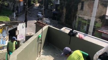 homem trabalha no piso com enxada. Espaço é na entrada de um morro. #paratodosverem