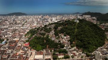 vista geral da cidade com massa de vegetação de morro à direita e a cidade em torno e à esquerda. #paratodosverem