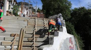 homens trabalham na construção de escadaria em morro. #paratodosverem