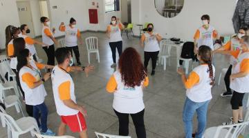 grupo de pessoas uniformizadas está em pé em roda. eles fazem movimentos com os braços. #paratodosverem