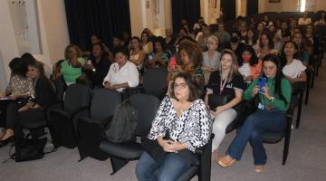 mulheres estão sentadas em auditório. #paratodosverem