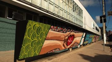 mural pintado em parede mostra quatro mãos estendidas segurando um coração. #paratodosverem