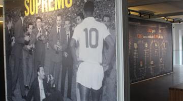 painel com uma foto mostrando o Rei Pelé de costas, com a camisa 10 e algumas pessoas engravatadas diante dele. No alto se lê Supremo. #paratodosverem
