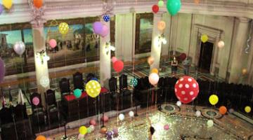 Balões ocupam do térreo ao teto do Museu do Café com público admirando.#pratodosverem