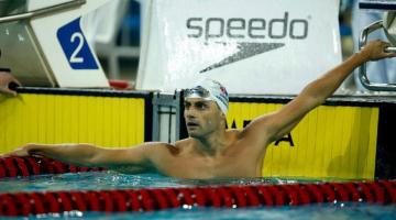 Leonardo de Deus está na piscina, em pé, com o peito e os braços para fora. #paratodosverem