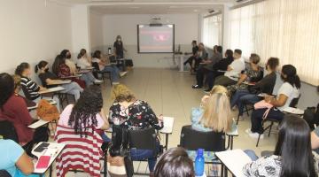 sala de aula com várias pessoas sentadas em roda assistindo a uma palestra. #paratodosverem