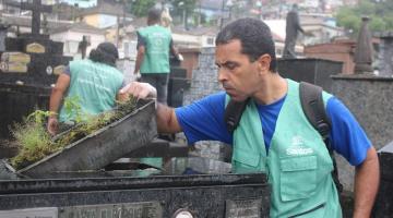 agente uniformizado examina depósito de vaso sobre túmulo. Outros agentes estão ao fundo. #paratodosverem 