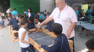 crianças fazem brincadeira em peça de madeira com a participação de um vovô sabe tudo. #paratodosverem 