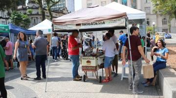 pessoas na praça com várias tendas #paratodosverem