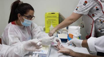 mulher retira gotinha de sangue de dedo de pessoa #paratodosverem