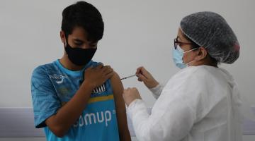 rapaz é vacinado  no braço #paratodosverem