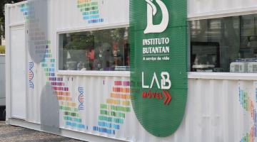 a fachada do labmóvel, com o logotipo do instituto butantan. O Labmóvel é um conteiner com parte fechada apenas por vidros, que permite ver o trabalho dos profissinais no interior. #paratodosverem