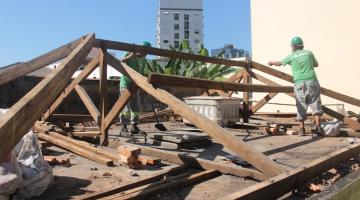 dois homens estão trabalhando em telhada com estrutura de telhas em madeira aparente. #paratodosverem