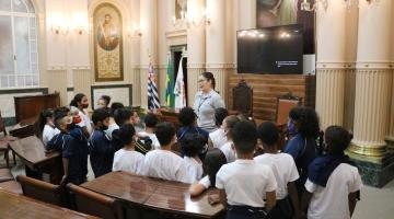 alunos escutam guia dentro de sala histórica #paratodosverem