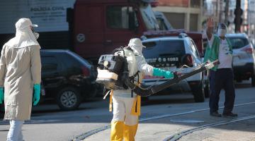 Homem com equipamento acoplado às costas pulveriza ambiente aberto. #Paratodosverem