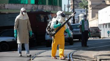 Um homem faz aplicação de inseticida e outro o acompanha. #Paratodosverem