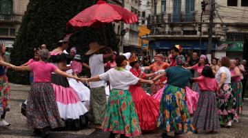 pessoas fantasiadas dançando em praça #paratodosverem