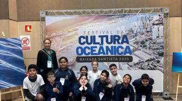 alunos posam na frente de placa do festival #paratodosverem