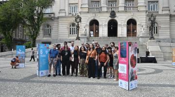 artistas reunidos na praça, na frente de exposição #paratodosverem