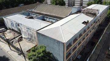 prédio de escola em obras, com tela protegendo uma das fachadas. #paratodosverem