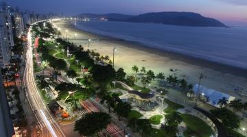 vista geral da avenida da orla à noite, em quase toda suas extensão, com as pistas iluminadas. #paratodosverem