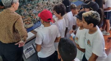 crianças observam maquete. #paratodosverem