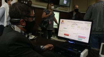 Homem olha para tela de computador com dados do painel da violência contra mulher. #pracegover