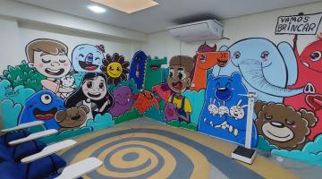 parede de hospital grafitada com imagens de crianças e animais coloridos. Um deles segura uma placa onde se lê 