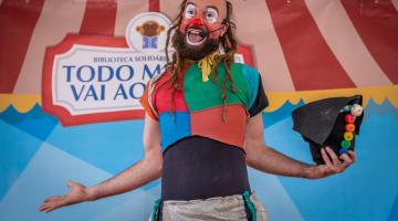 palhaço lixolino está sorrindo, com os braços abertos e segurando um chapéu na mão esquerda. #paratodosverem