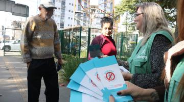 pessoas recebendo panfletos de agentes #paratodosverem 