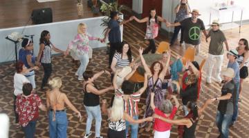 mulheres dançam em roda em um salão. #paratodosverem