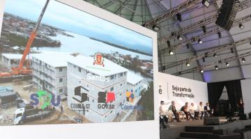 em primeiro plano, tela mostra obra e ao fundo os debatedores #paratodosverem