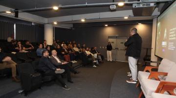 Pessoas no auditório acompanhando o evento #paratodosverem 